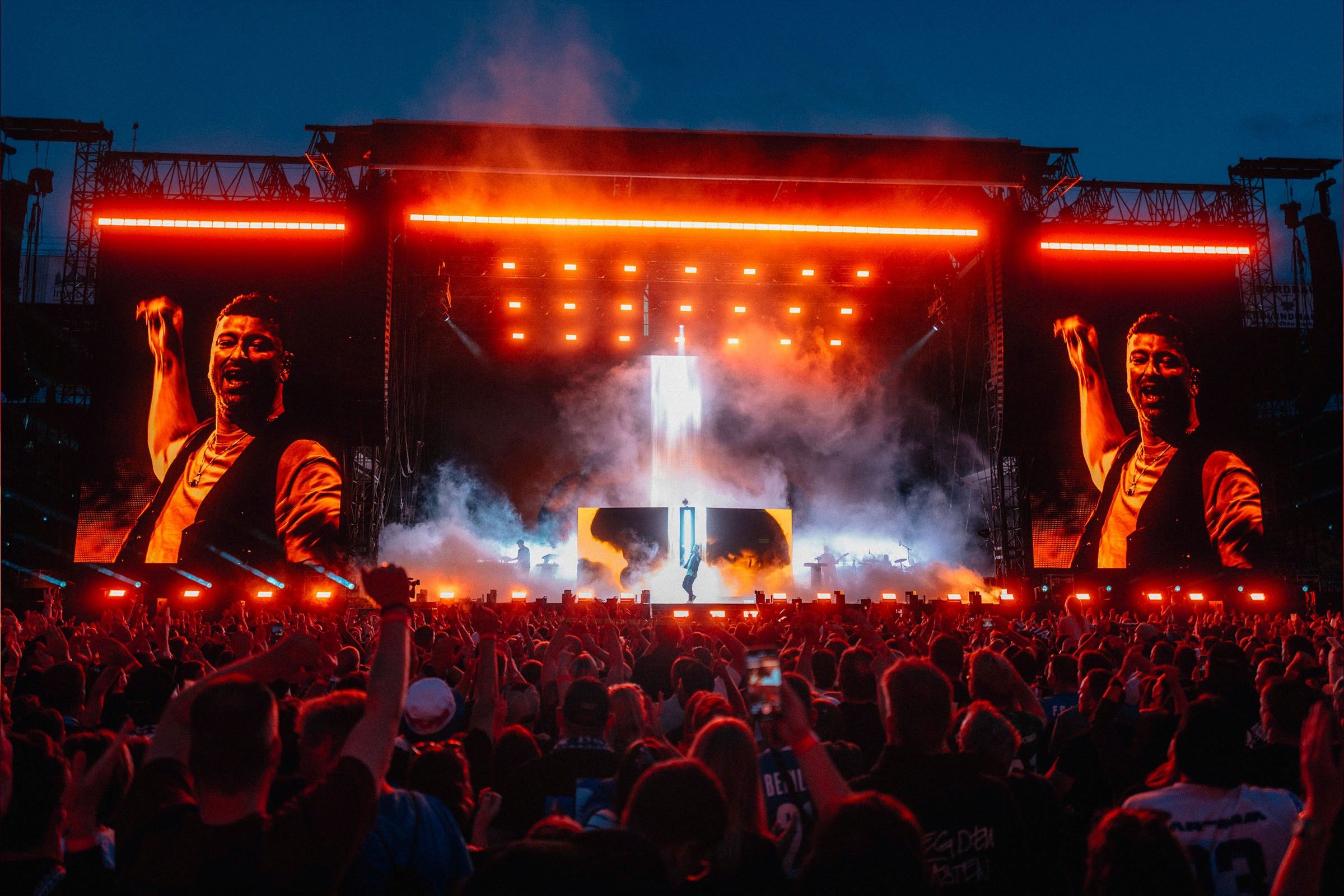 Marteria Vollkontakt Tour: Open-Air-Bühne in rotem Licht mit LED-Screens vor dem Publikum