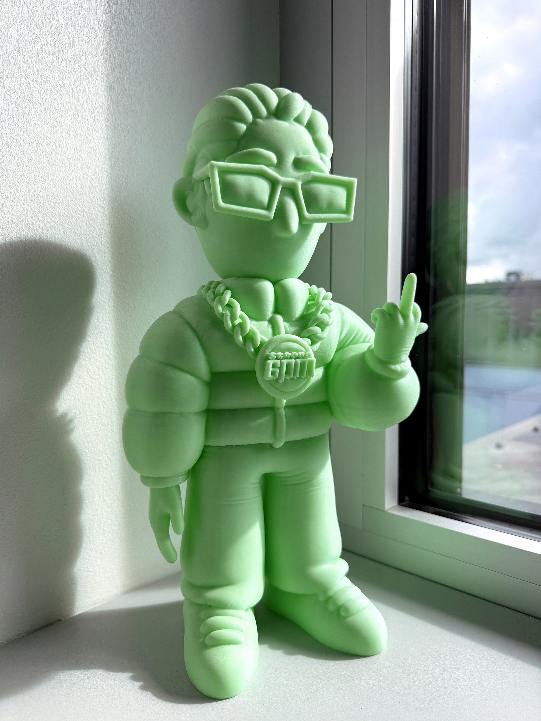Grüne 3D-gedruckte Figur von 6PM-Gründer Achraf mit Sonnenbrille, ein Prototyp von ST. ROBO