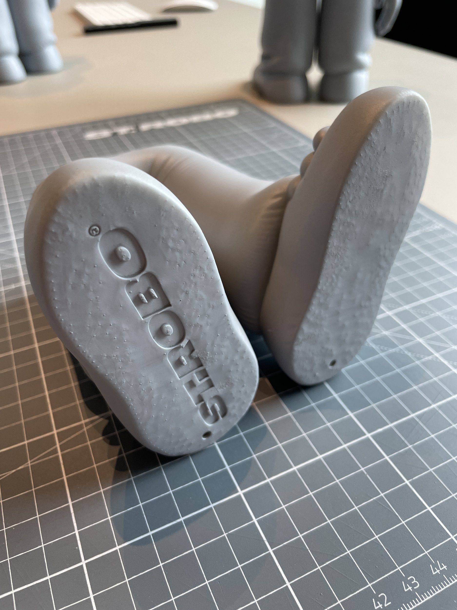 Grauer 3D-gedruckter Prototyp von Puffer-Boots auf einer Schneidematte
