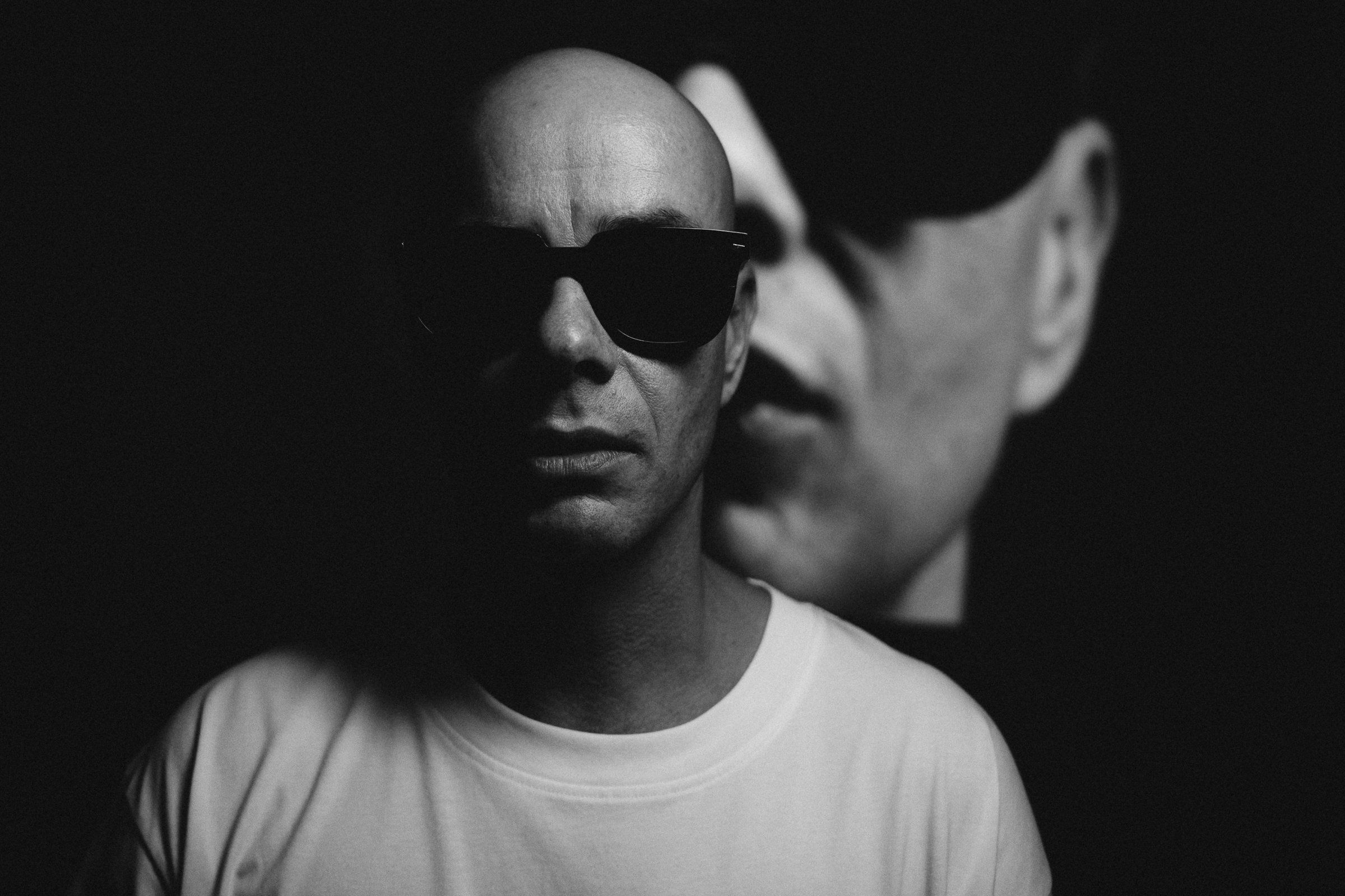 Black-and-white portrait of Trettmann in sunglasses with a second face in the foreground