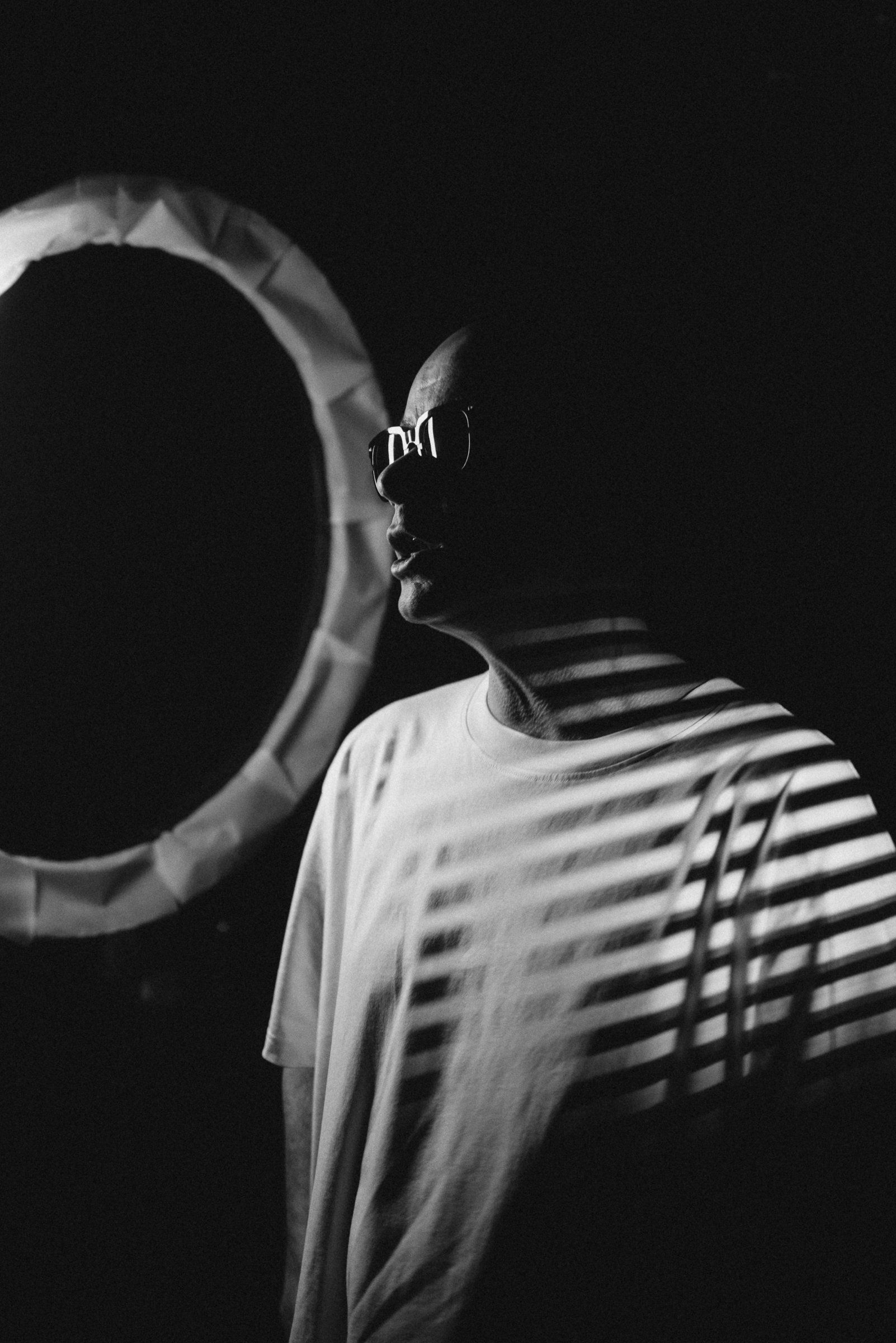 Trettmann in profile next to the ring light with projected light stripes