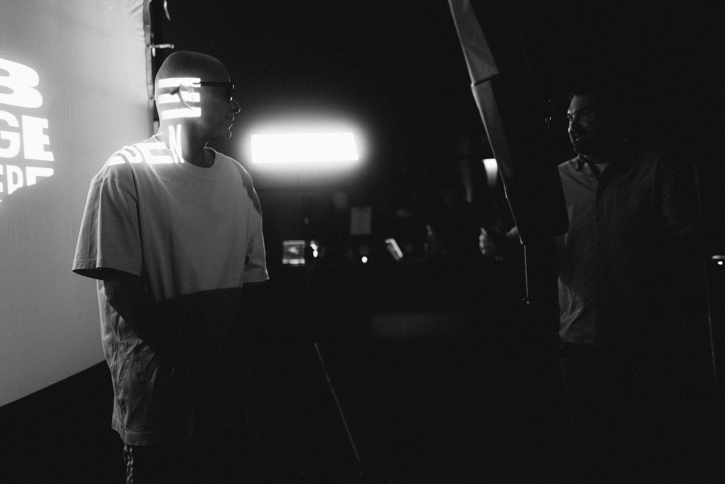 Trettmann on set in front of projected text with a bright light behind him