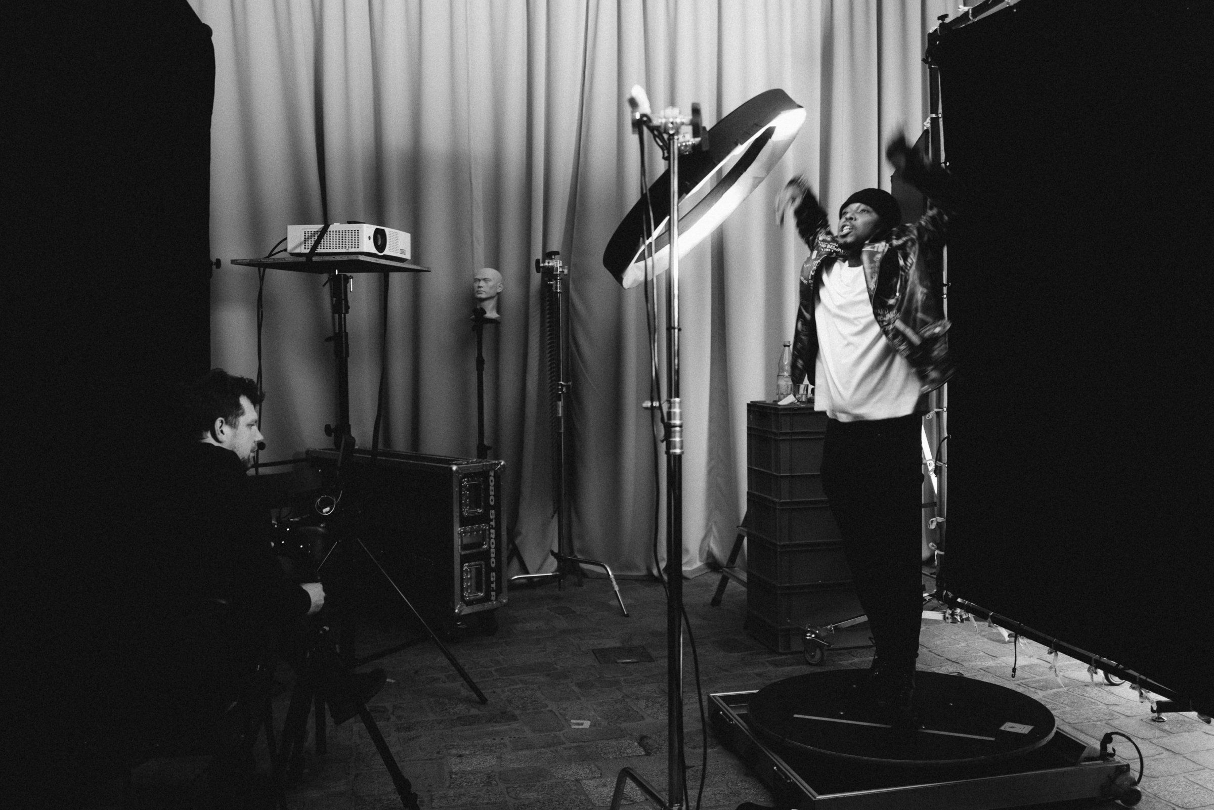 Performer on the turntable lit by the ring light while the crew films